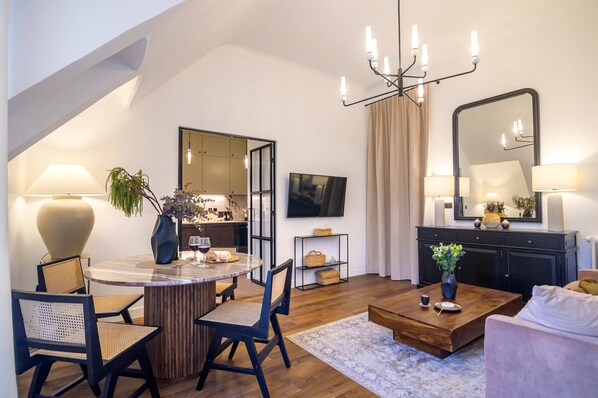 A modern living room with a dining area, a large mirror, and a chandelier.