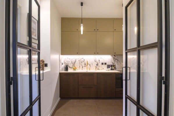A modern kitchen with wooden cabinets, a marble countertop, and a pendant light. - Balcon Champs Elysees (Paris)