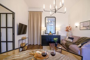 A modern living room with a sofa, a dining table with a meal, a TV, and a mirror. - Balcon Champs Elysees (Paris)