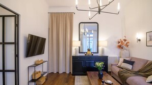 A modern living room with a flat-screen TV, a dark wooden coffee table, a beige sofa, and a black console table with decorative items. - Balcon Champs Elysees (Paris)
