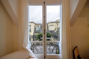 A room with a large window overlooking a balcony with outdoor furniture. - Balcon Champs Elysees (Paris)