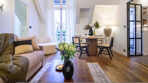 A modern living room with a sofa, a dining table with chairs, a vase with flowers, and a lamp. - Balcon Champs Elysees (Paris)