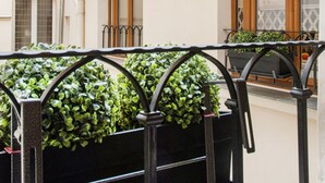 A courtyard with a black metal railing, potted plants, and a building with balconies and windows. - Le Diamant En Isle - Ile Saint Louis (Paris)