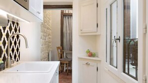 A compact kitchen with a white sink, a wooden chair, and a cabinet with a frosted glass door. - Le Diamant En Isle - Ile Saint Louis (Paris)