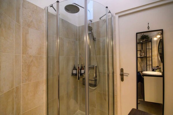 Un baño moderno con ducha de vidrio, lavamanos y espejo.