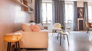 A modern living room with a sofa, a coffee table, and a bookshelf. - Le Gourmet du Marais (Paris)
