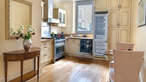 A kitchen with wooden cabinets, a stove, and a dishwasher. - La Lumiere Eiffel Walk to Tower (Paris)