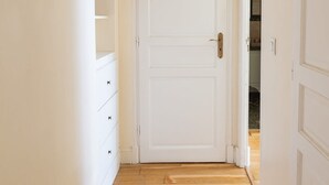 A white door with a brass handle, a white wardrobe with a mirror, and a wooden floor. - La Lumiere Eiffel Walk to Tower (Paris)