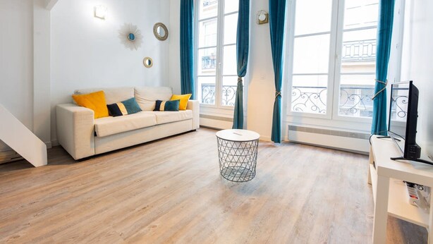 A modern living room with a sofa, a round side table, and a TV stand. - Le Loft Latin - New Apt (Paris)