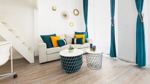 A modern living room with a staircase, a white sofa with teal and yellow cushions, two round coffee tables, and teal curtains. - Le Loft Latin - New Apt (Paris)
