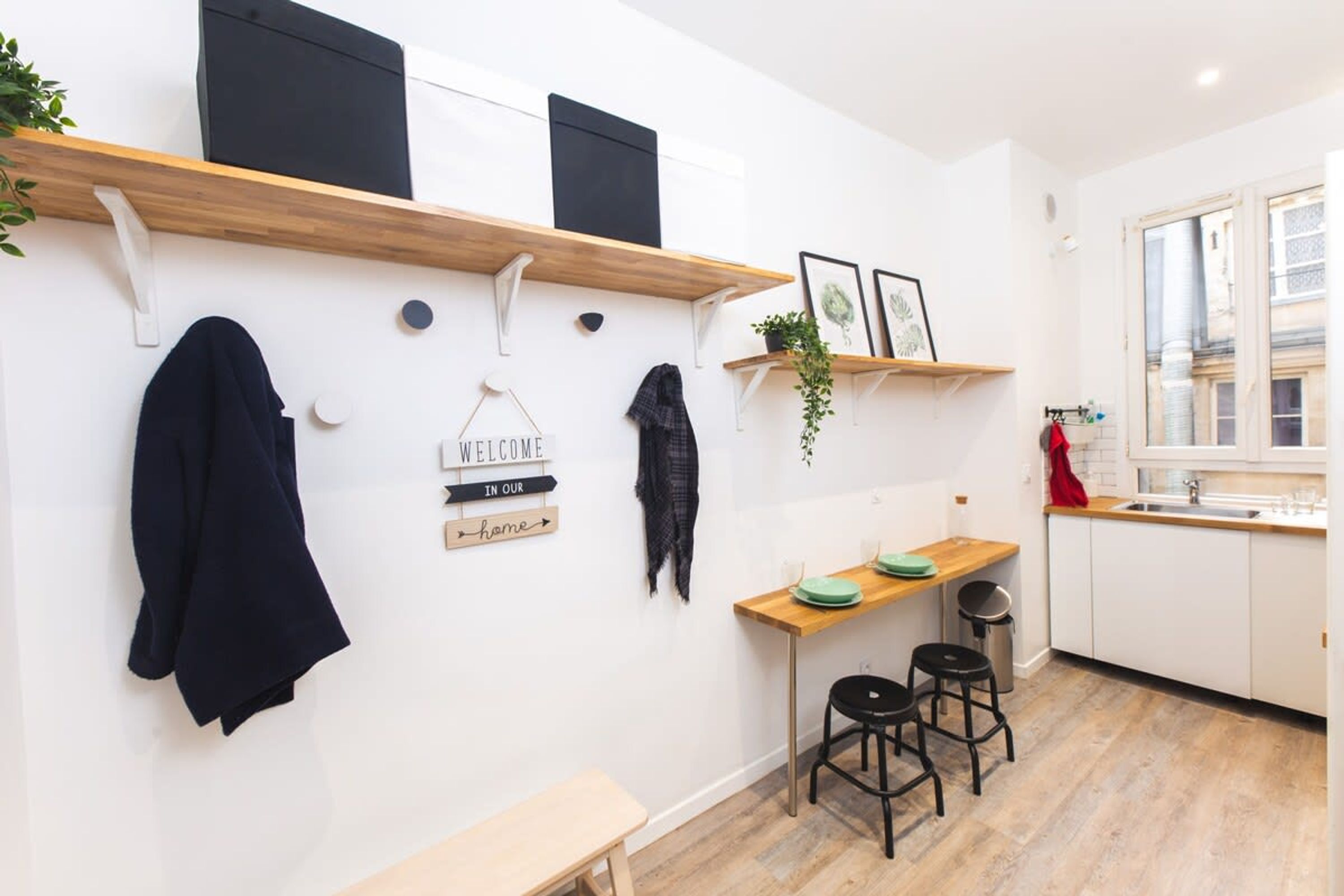 A modern kitchen with wooden shelves, a welcome sign, and a bench.