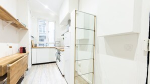 A modern kitchen with white cabinets, a wooden countertop, and a glass door. - Le Loft Latin - New Apt (Paris)