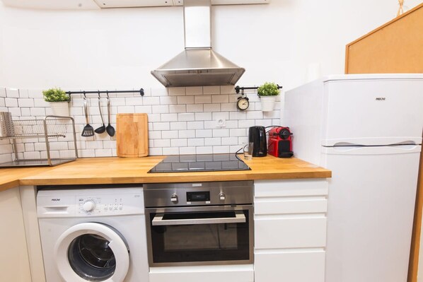 Eine kompakte Küche mit Waschmaschine, Backofen und einem weißen Kühlschrank.