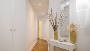 A hallway with a white console table, a mirror, and decorative branches. - Le Balcon de Notre Dame (Paris)