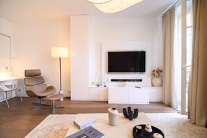 Un salon moderne équipé d’un téléviseur à écran plat, d’un canapé, d’un bureau et d’une lampe.
