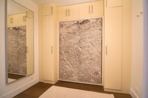 A room with a large map artwork on the wall, wooden flooring, and white cabinets. - Le Balcon de Notre Dame (Paris)