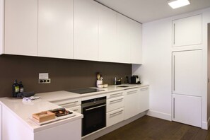 A modern kitchen with white cabinetry, a built-in oven, and a dishwasher. - Le Balcon de Notre Dame (Paris)