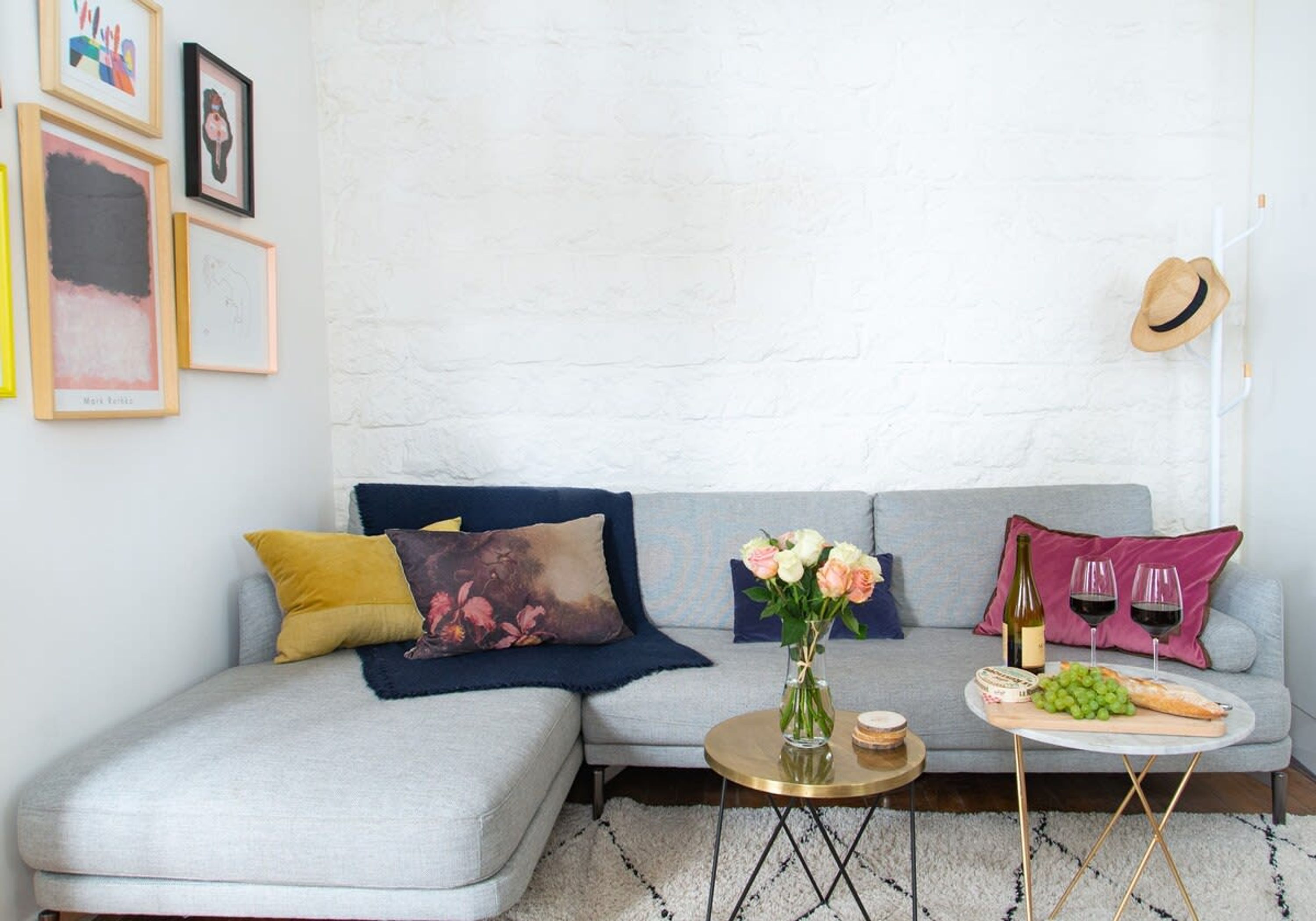 A modern living room with a grey sectional sofa, a round coffee table, and a small side table with a bottle and glasses.