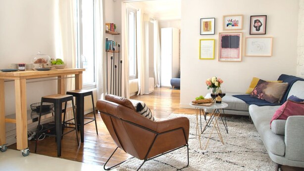 A modern living room with a sofa, a coffee table, and a dining area with a table and chairs. - Le Plaisir du Pantheon (Paris)