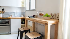 A modern kitchen with a wooden table, two stools, a bread display, and a 'love' decoration. - Le Plaisir du Pantheon (Paris)
