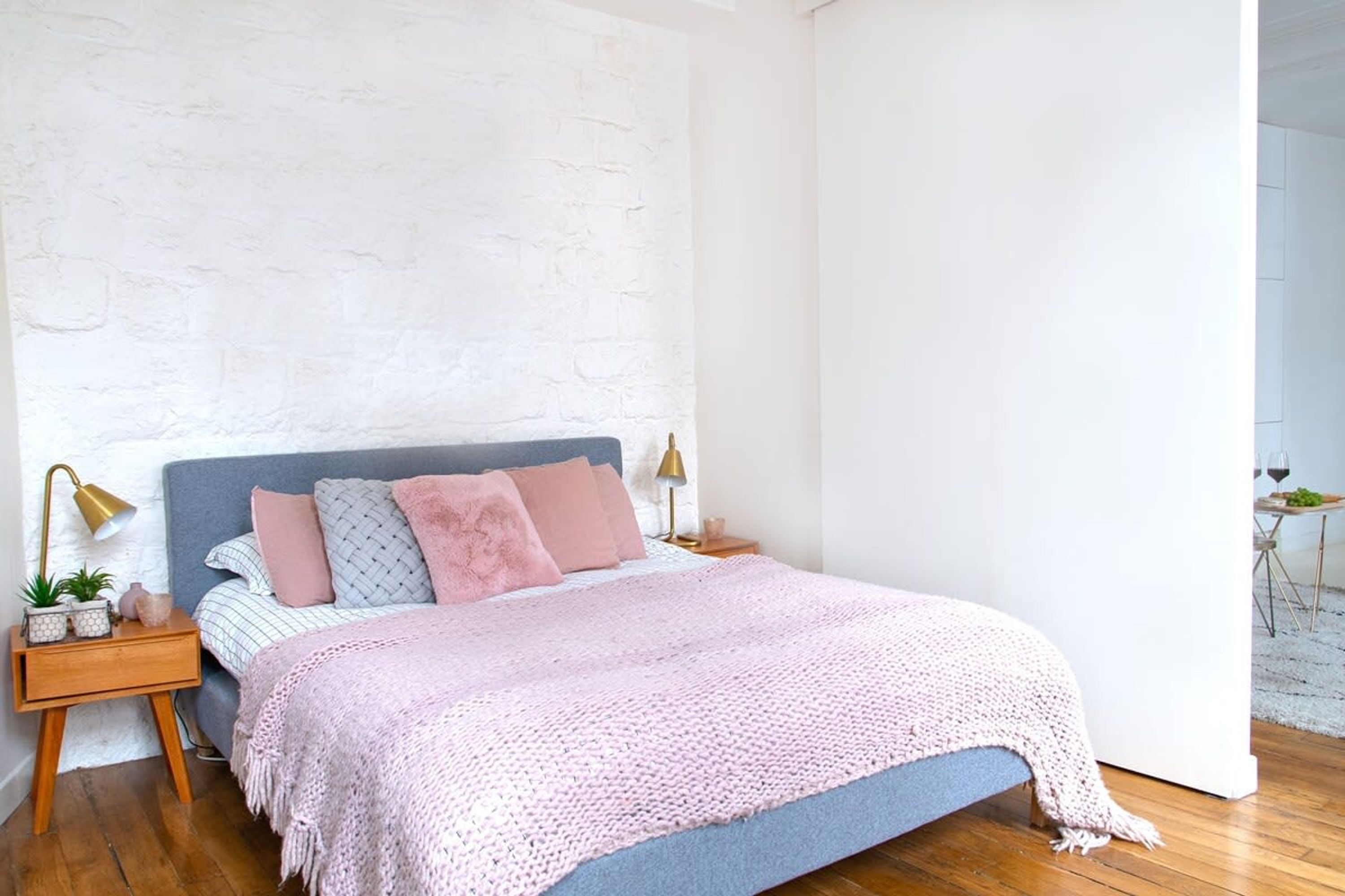 Ein Schlafzimmer mit einem Bett, Nachttischen aus Holz, einer weißen Ziegelwand und einem Holzboden.