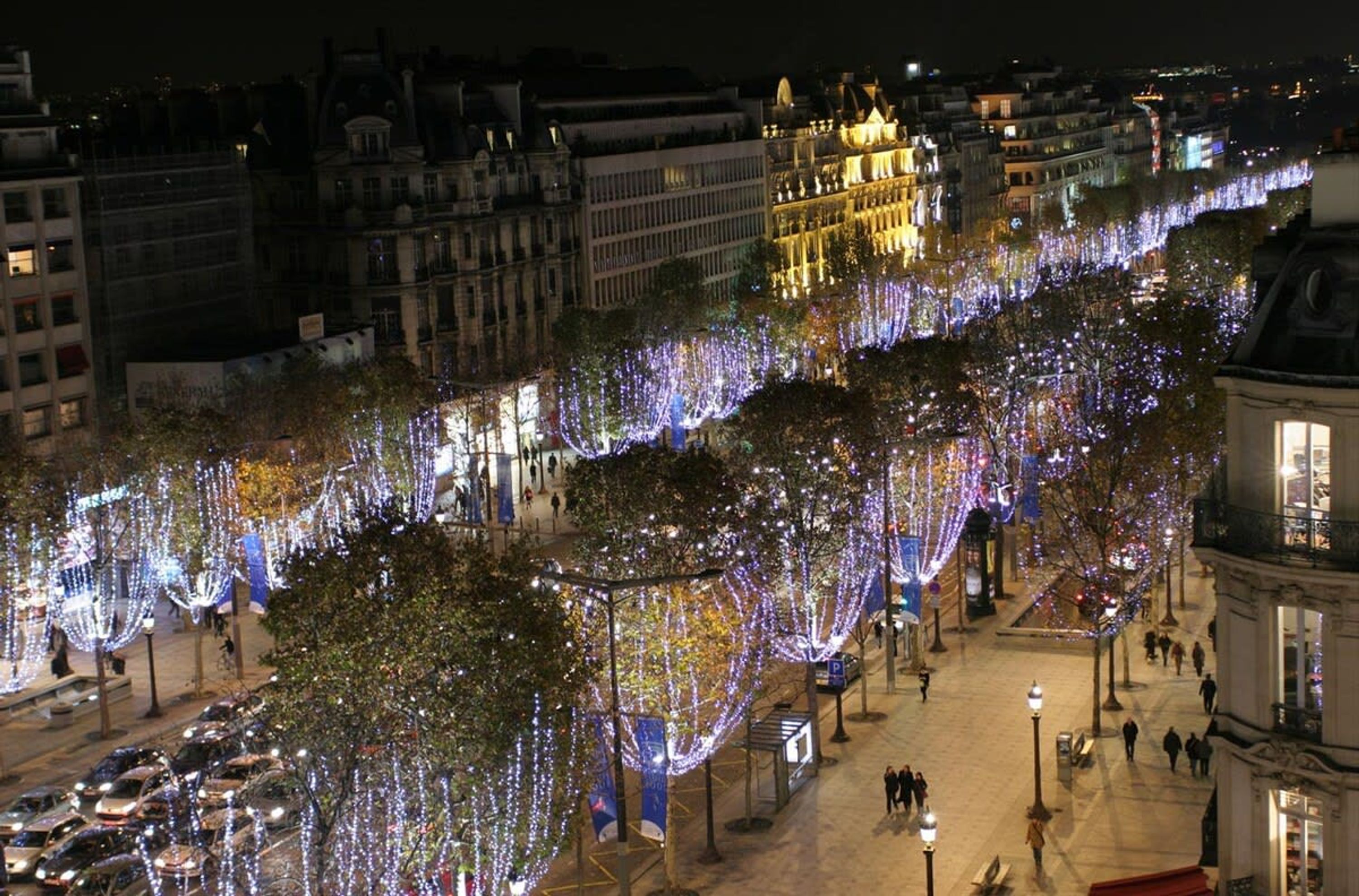 A nighttime cityscape with illuminated trees and buildings.