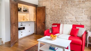 A cozy living room with a red sofa, a white coffee table, and a stone wall. - Studio en Isle - Monthly Rental (Paris)