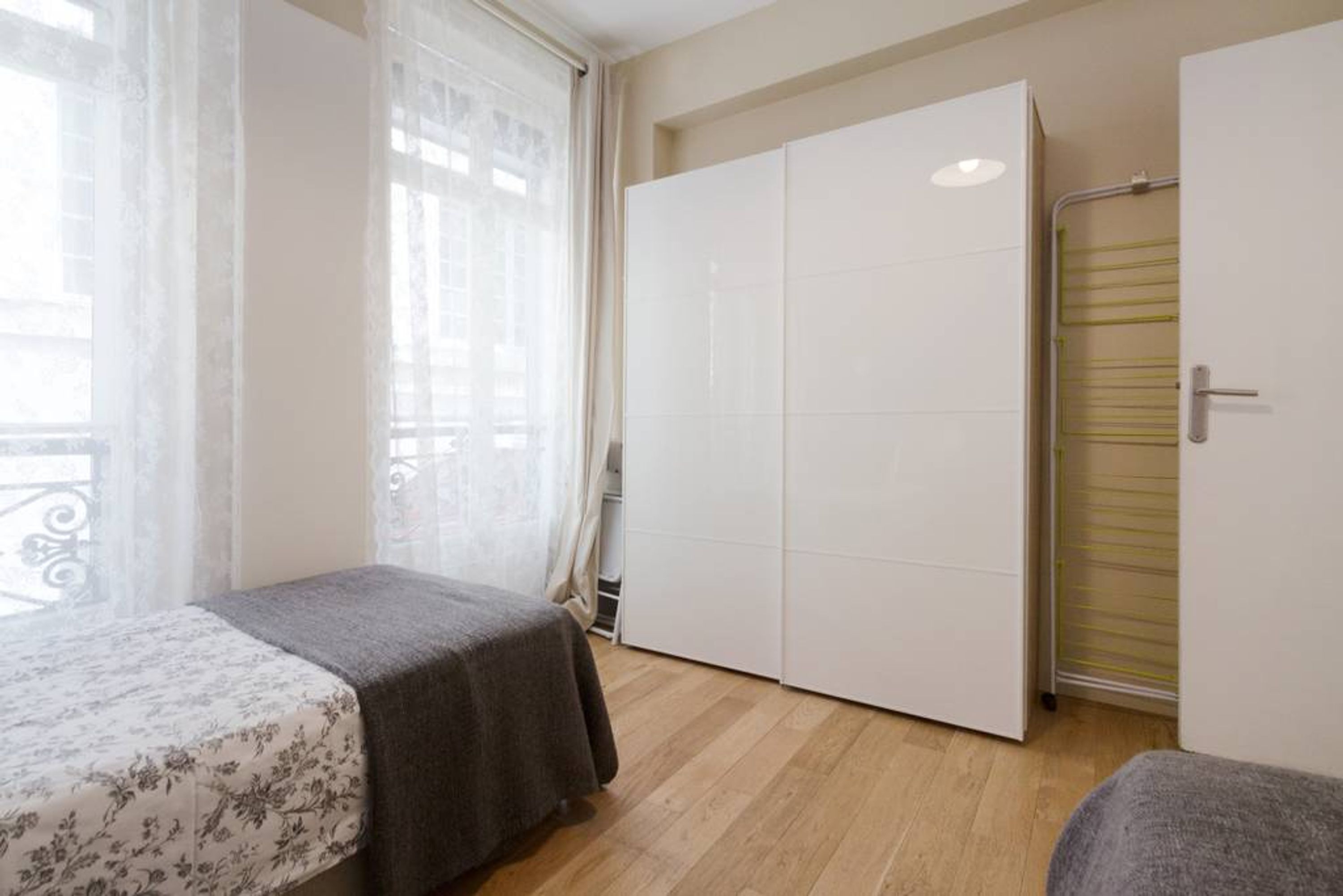 Ein Schlafzimmer mit einem Bett, einem Kleiderschrank und einem Fenster mit Vorhängen.