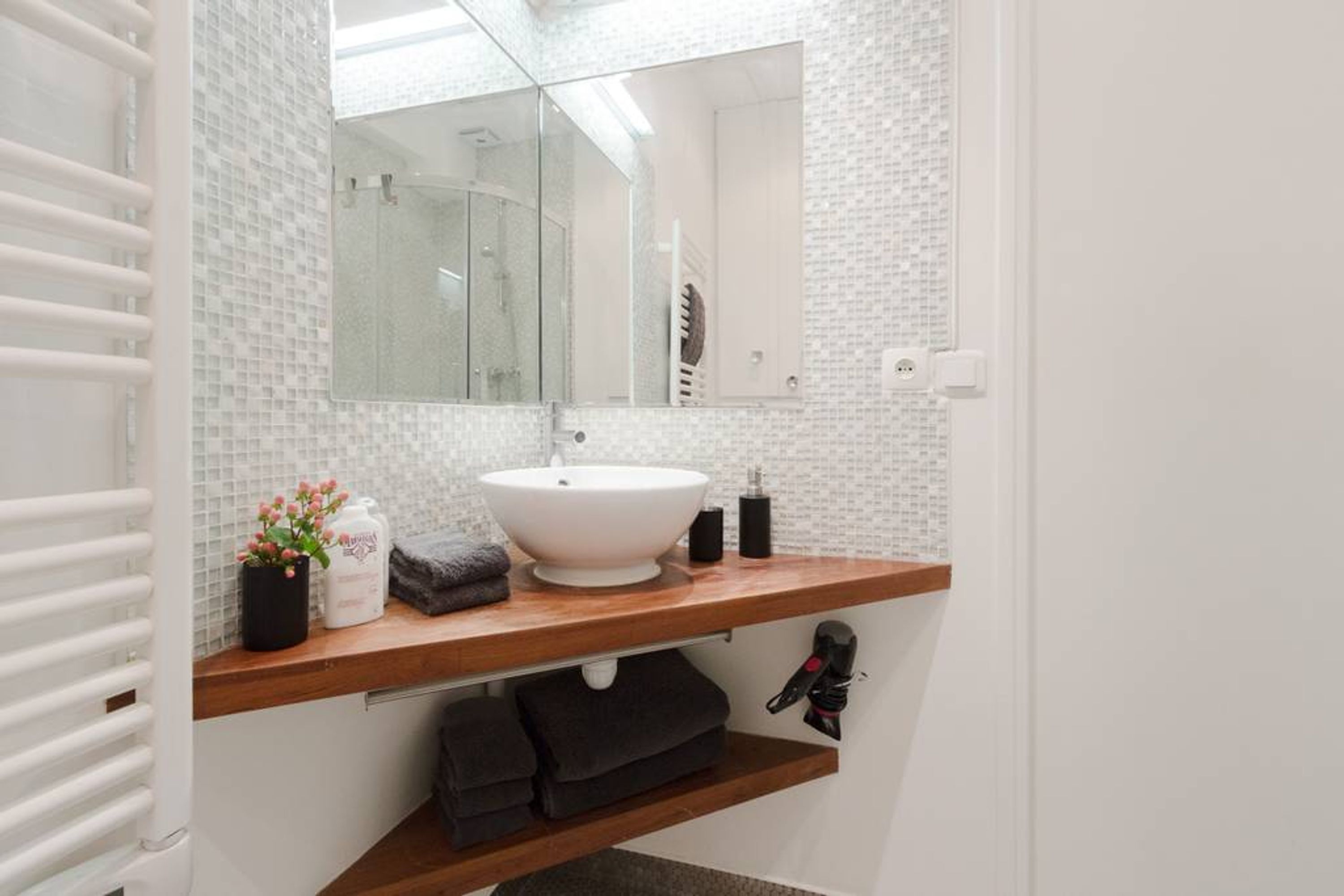 A bathroom with a white sink, a mirror, a towel rack, and a shower area.