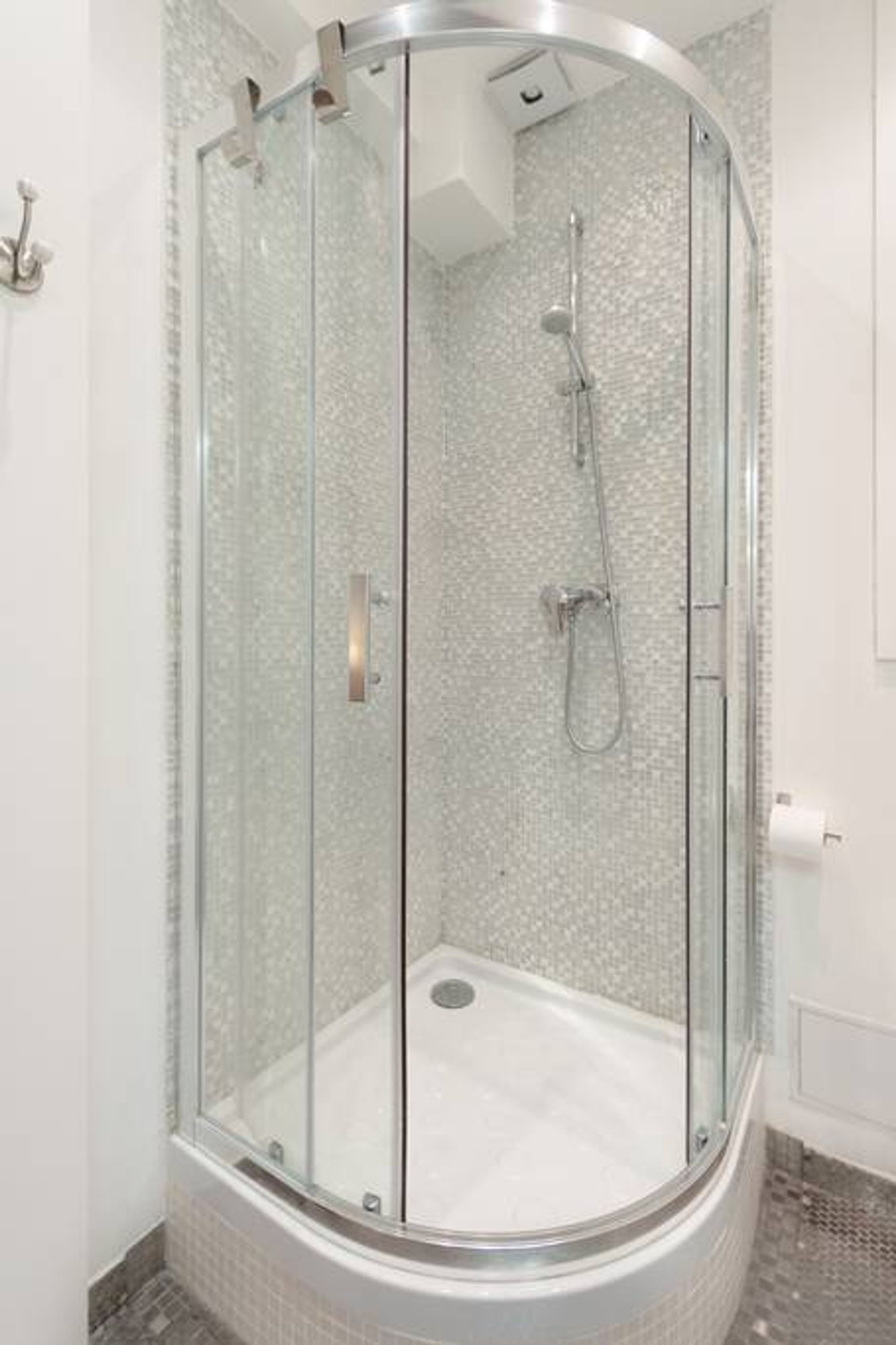 A glass-enclosed shower stall with a tiled floor and a showerhead.