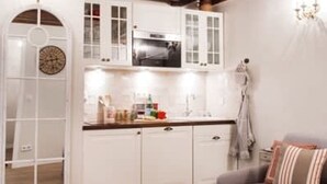 A cozy kitchen with white cabinets, a microwave, and a wooden ceiling. - Le Merlot du Marais - Pompidou (Paris)