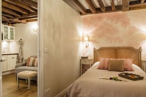 Une chambre à coucher comprenant un lit, des tables de chevet, une commode, une coiffeuse et une fenêtre.