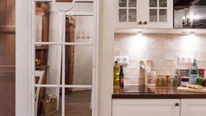 A kitchen with white cabinets, a wooden floor, and a hanging light fixture. - Le Merlot du Marais - Pompidou (Paris)