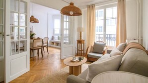 A spacious living room with a sofa, a coffee table, and a dining area with chairs and a table. - Deco St Antoine in Paris (Paris)