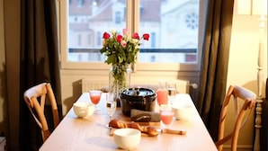 Une table à manger ornée d’un vase de fleurs, avec un autocuiseur et des aliments pour le petit-déjeuner.