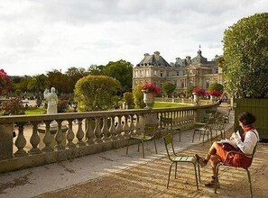 A courtyard with a stone balustrade, a statue, and a building in the background. - Loft Saint Germain - Bon March (Paris)