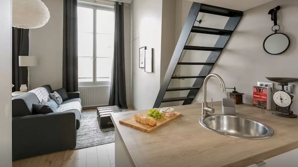 Une cuisine moderne dotée d’un évier encastré, d’un plan de travail en bois et d’un coin repas comprenant un canapé et une lampe.