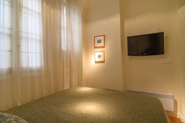A bedroom with a bed, a TV mounted on the wall, and two framed pictures. - Le Marais Moderne in Paris (Paris)