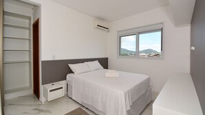 Ein Schlafzimmer mit Bett, Nachttisch, Kleiderschrank und einem Fenster mit Blick.