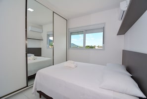 A bedroom with a bed, a window, and a mirror.