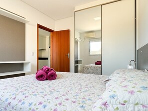 A bedroom with a bed, a wardrobe, a mirror, and a window. - Residencial Fiametti-Praia dos Ingleses (Florianopolis)