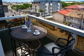 A balcony with wicker furniture, a white cup, and a vase with purple flowers. - Residencial Fiametti-Praia dos Ingleses (Florianopolis)