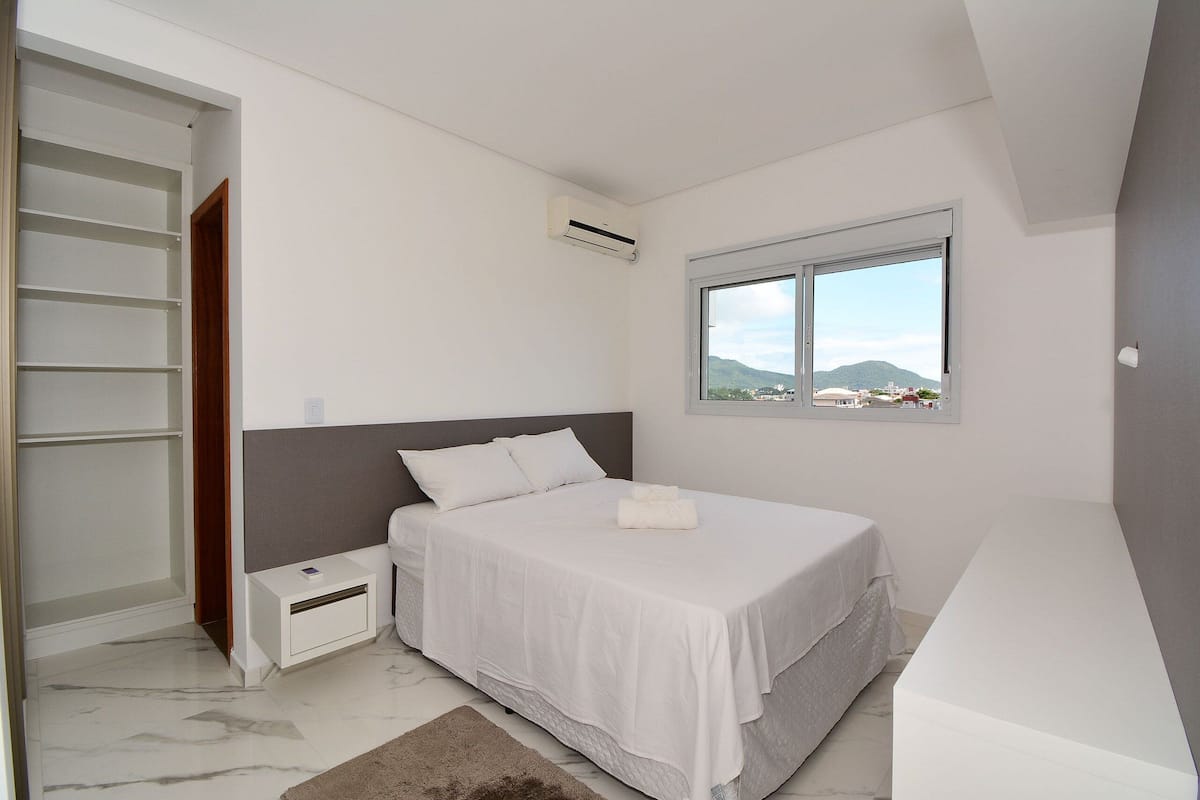 Une chambre à coucher avec un lit, une table de chevet, une armoire et une fenêtre donnant sur un beau paysage.