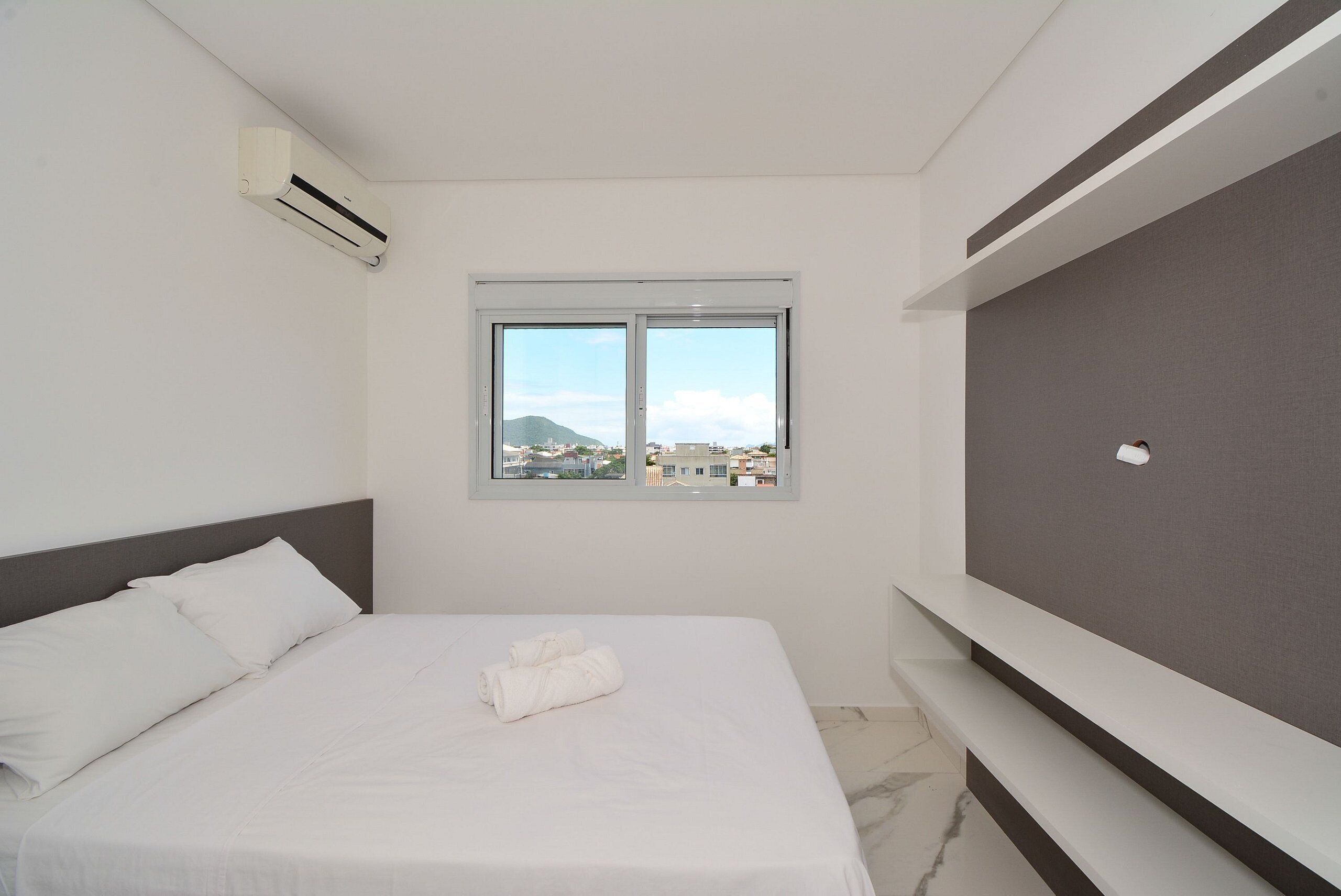 A hotel room with a bed, a window, and an air conditioning unit.