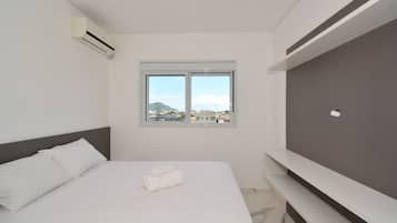 A hotel room with a bed, a window, and an air conditioning unit.