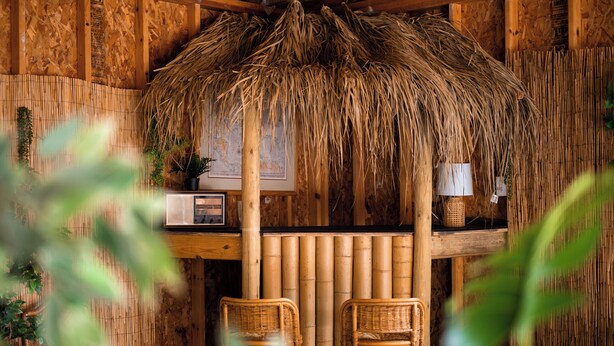 A rustic wooden interior with a thatched roof, two wicker chairs, a wooden bar counter, and a map on the wall. - Tiki Bar! Near wineries, Sleeping Bear Dunes, TC - Cedar Cottage (Cedar)