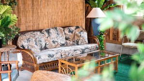 A wicker sofa with a leaf pattern, a glass coffee table, and a bamboo wall. - Tiki Bar! Near wineries, Sleeping Bear Dunes, TC - Cedar Cottage (Cedar)