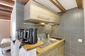 Una cocina compacta con cubierta de madera, horno integrado y un lavamanos.