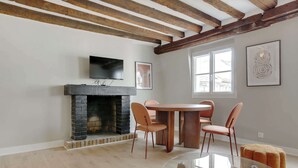 Un área de comedor con chimenea, un televisor montado encima y una ventana con vistas.