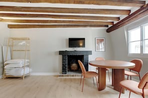 Una habitación con chimenea, un televisor colocado encima y una mesa redonda de madera con sillas.